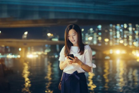 Asian woman smartphone Hong Kong city skyline night
