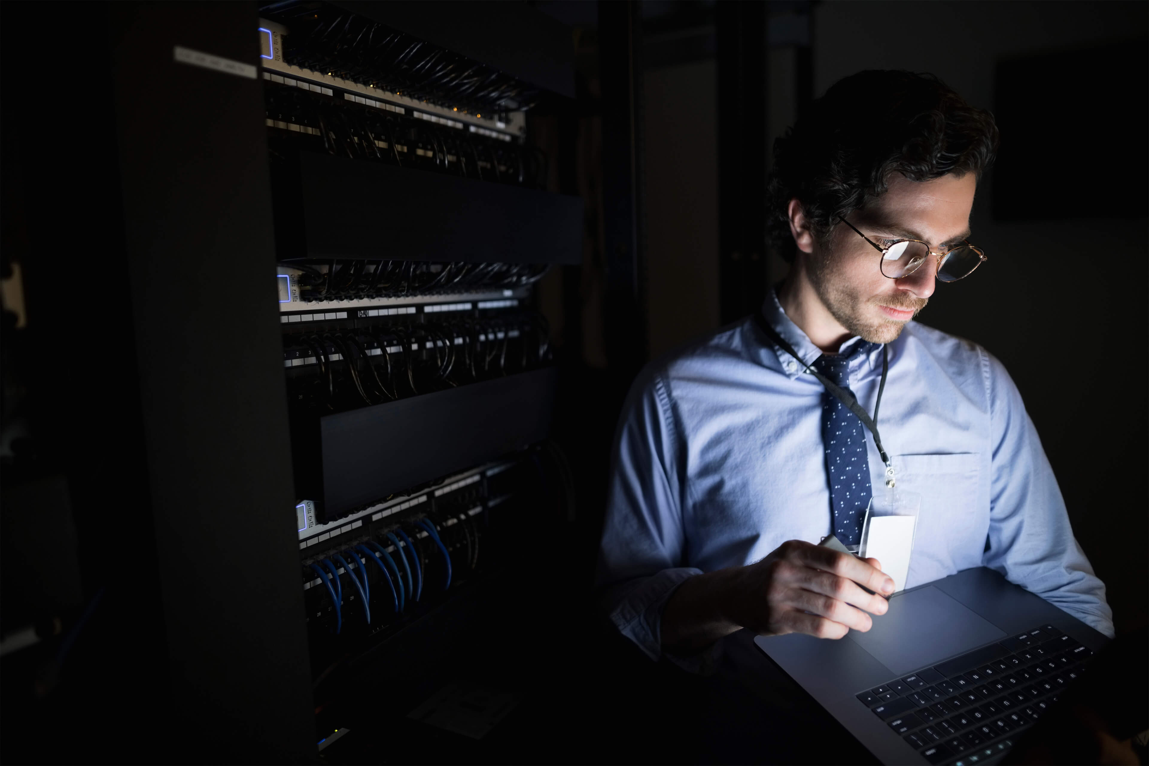Man checking tablet dark server room image