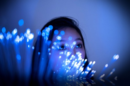 Young asian woman standing on glowing fiber optic background